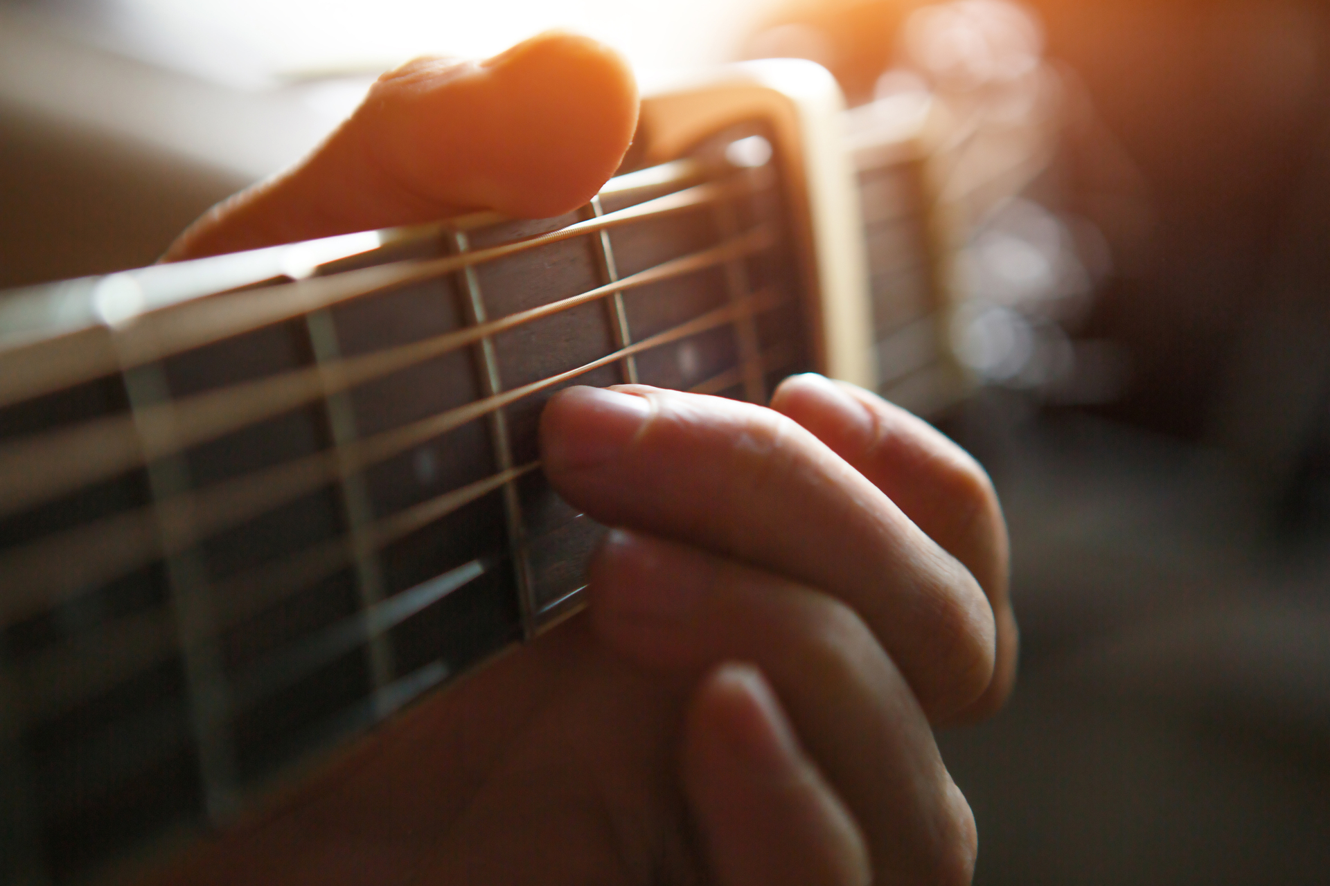 1920-a-man-s-hand-on-the-fretboard-of-a-guitar-runs-his-fingers-through-the-strings-and-clamps-the-chords-instrumental-music-guitar-lesson-on-sheet-music.jpg