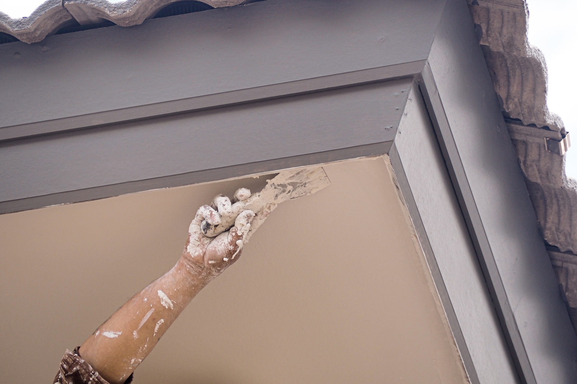 1920-a-painter-is-painting-the-exterior-under-the-eaves-of-a-gray-concrete-roof.jpg