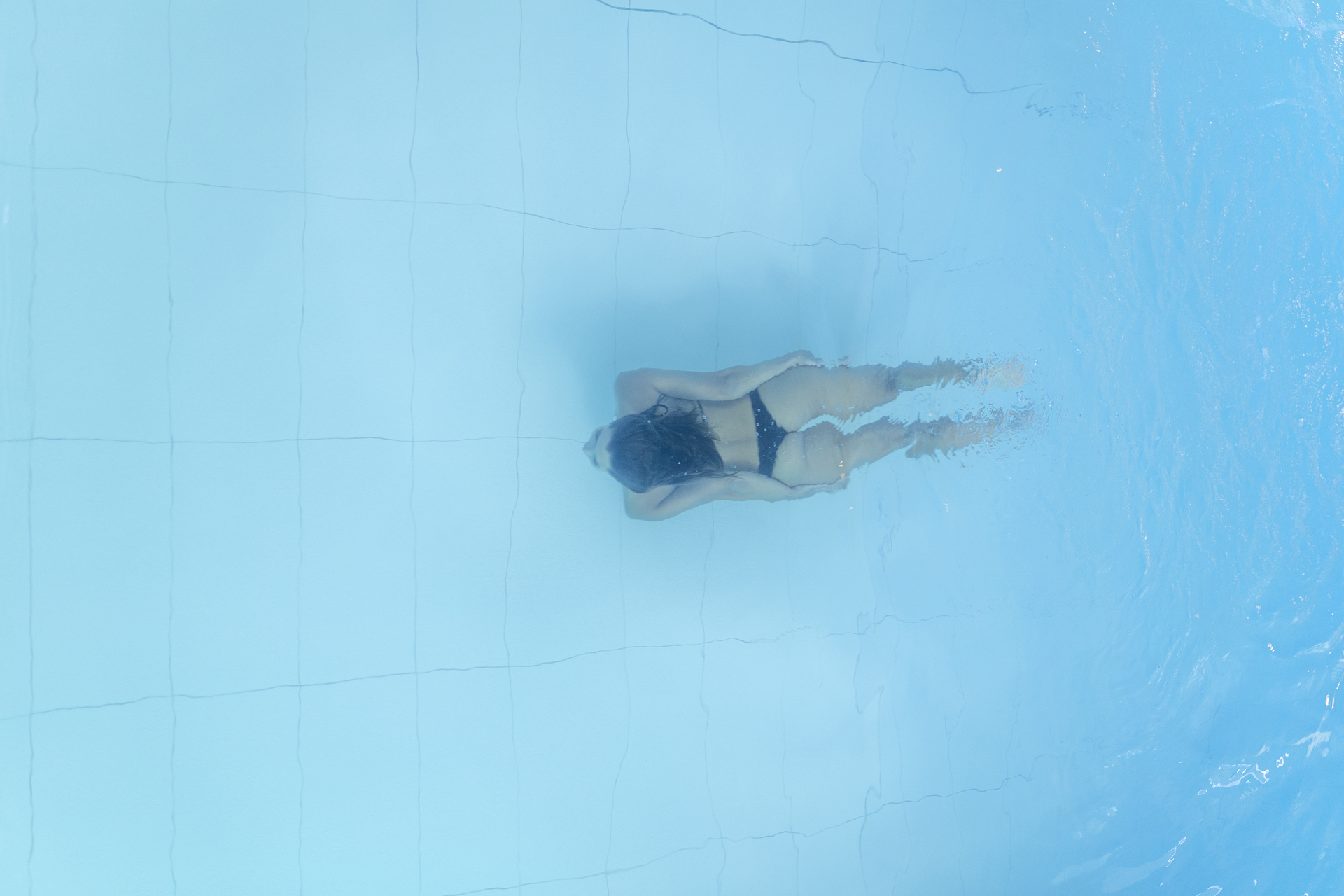 1920-attractive-young-woman-floating-in-a-swimming-pool-with-her-arms-outstretched-looking-at-the-sky.jpg