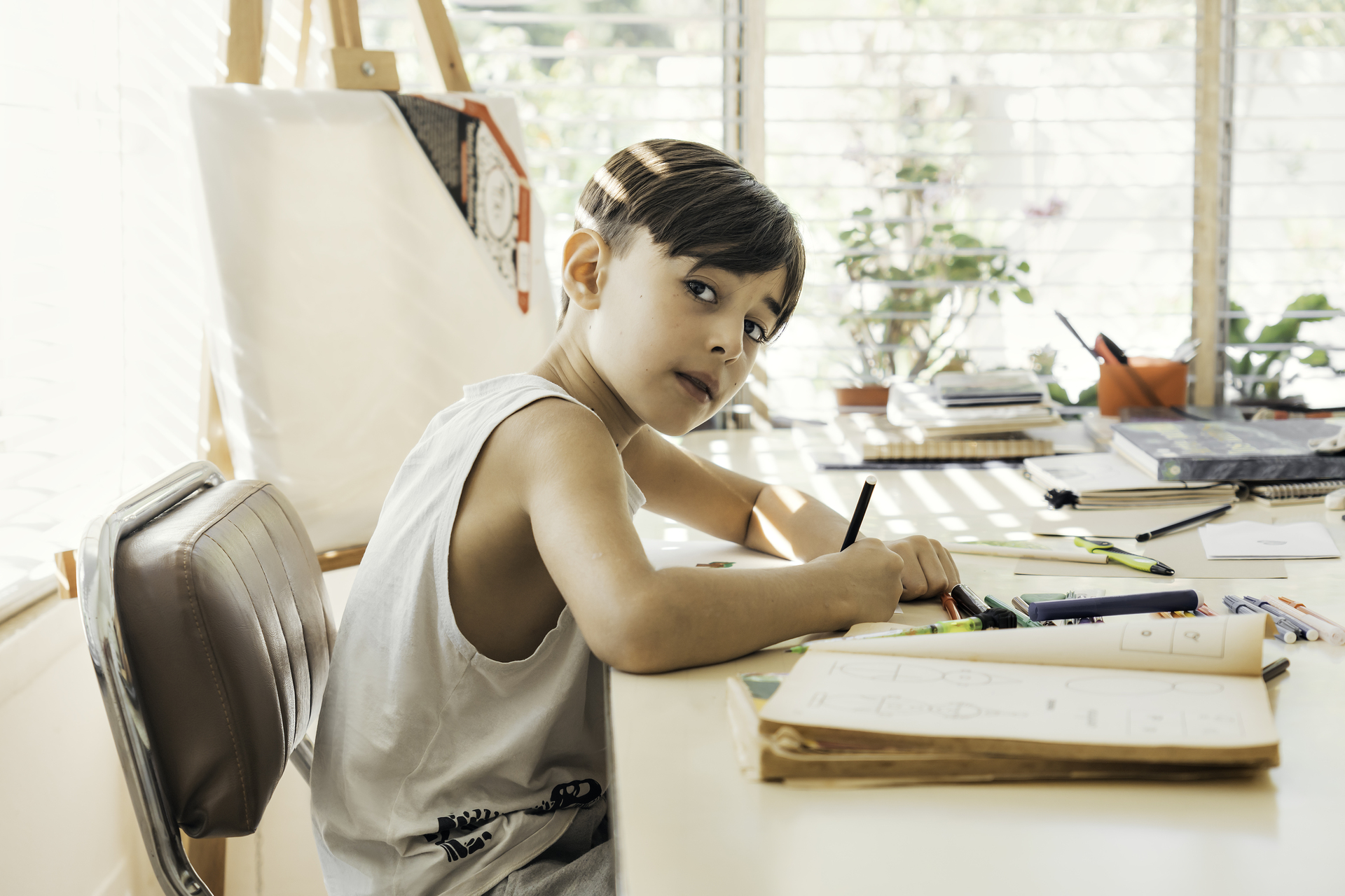 1920-boy-sitting-in-his-drawing-class-with-a-pen-in-his-hand-drawing-and-coloring.jpg