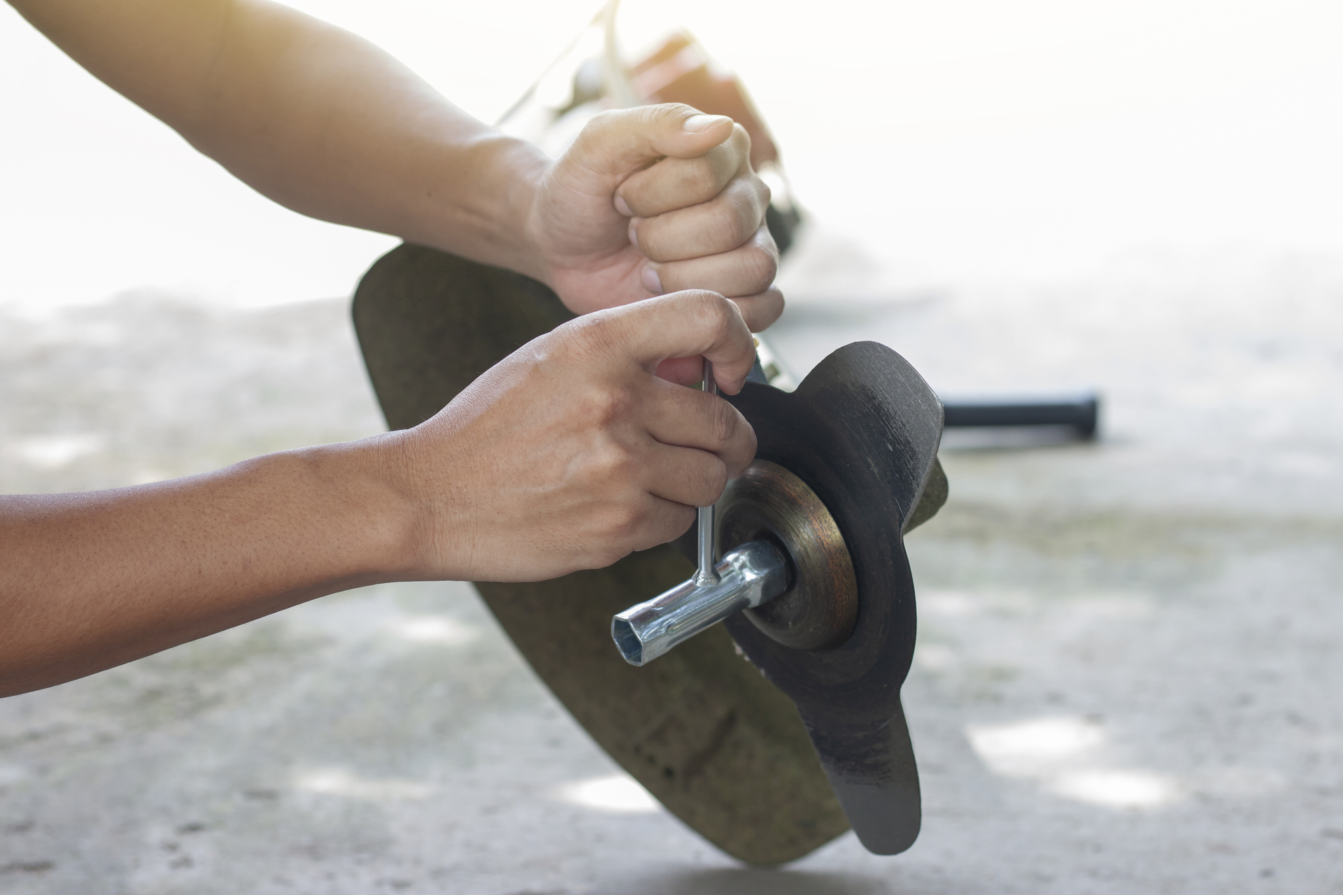 1920-hand-of-the-mechanic-holds-the-socket-wrench-to-loosen-the-nut-in-the-lawn-mower.jpg