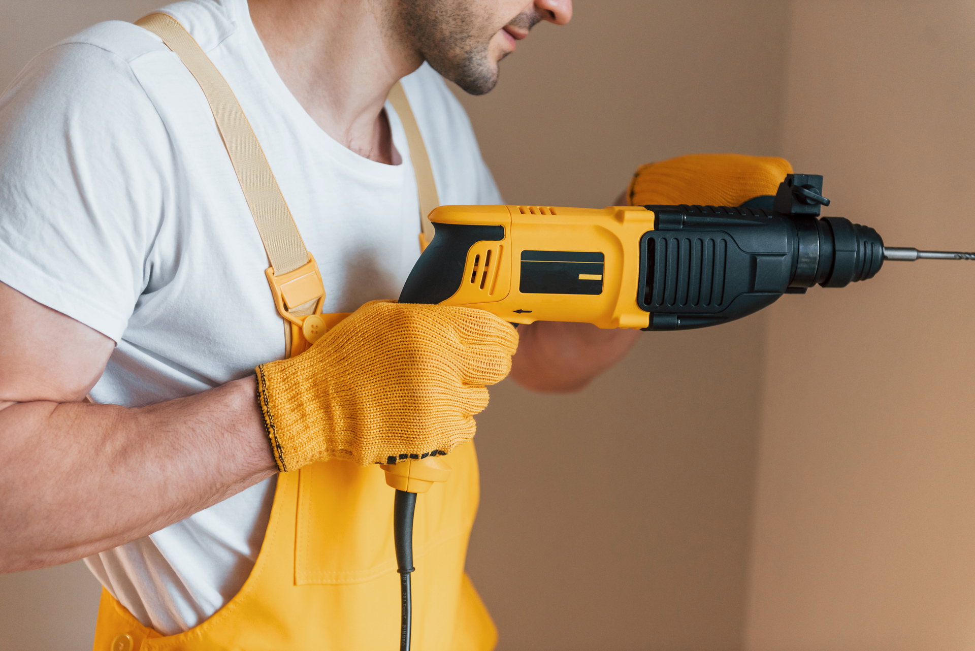 1920-handyman-in-yellow-uniform-works-indoors-by-using-hammer-drill-house-renovation-conception.jpg