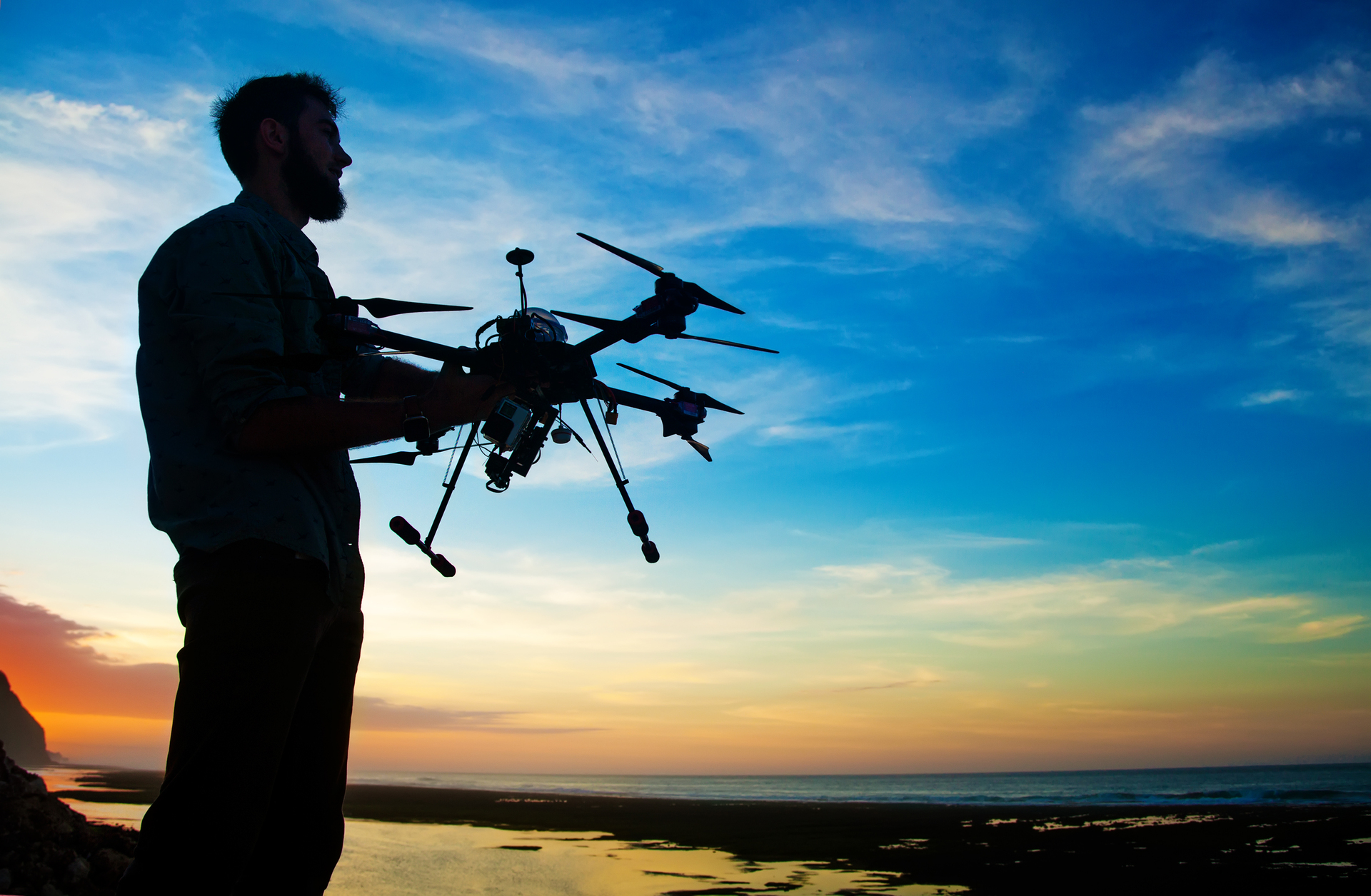 1920-manholding-a-drone-for-aerial-photography-silhouette-against-the-sunset-sky.jpg